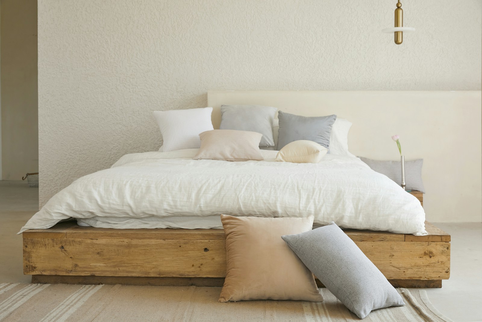 un lit avec plusieurs oreillers blancs, gris et marrons